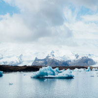 an ice cap floating in the water with mountains in the background